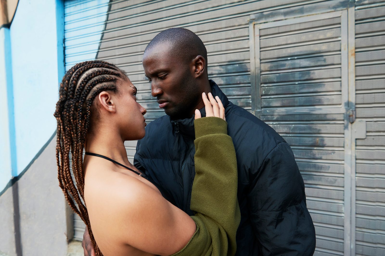 Two people facing each other in front of a metal shutter