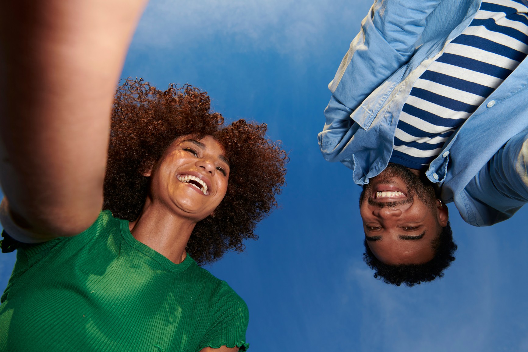Two people smiling for a photo against a blue sky