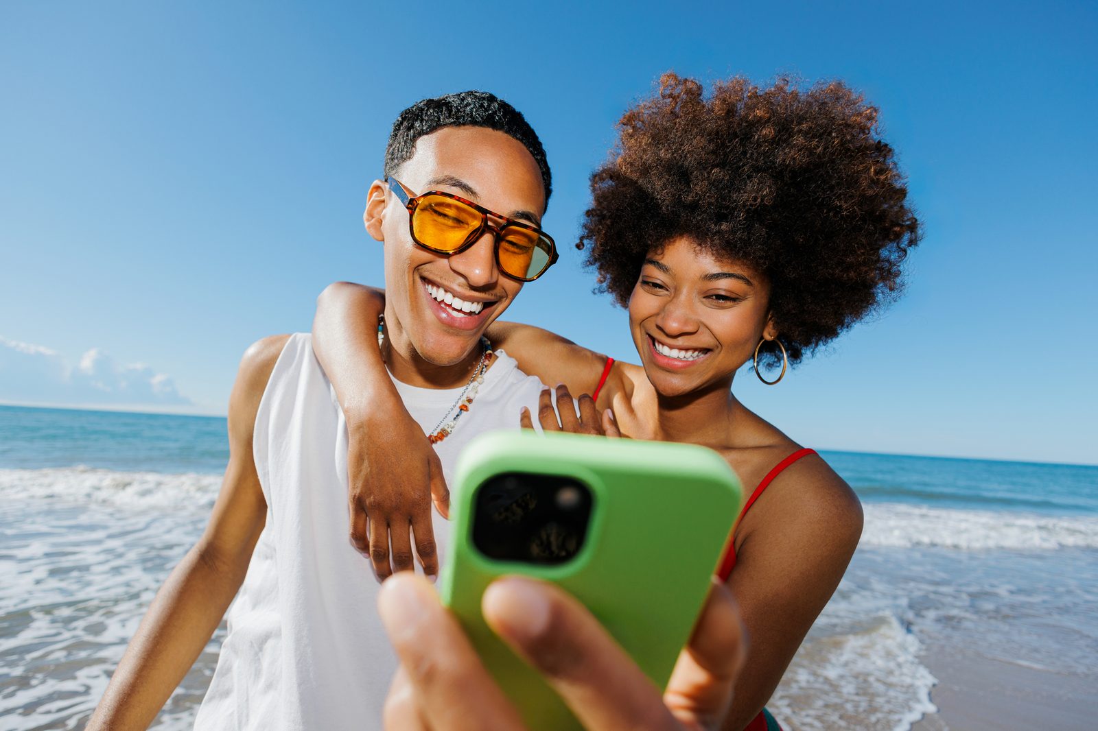 Two people on a beach looking at a phone together