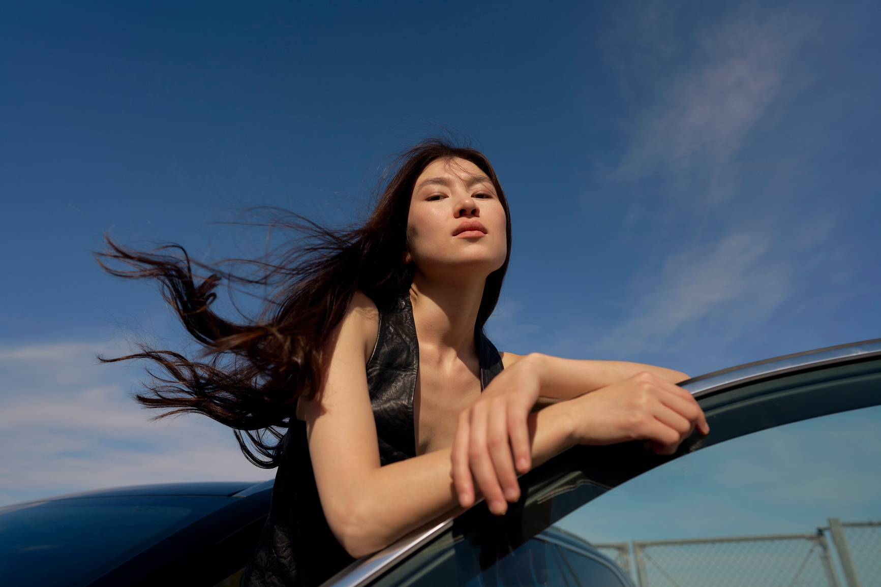 Frau, die sich unter blauem Himmel an ein Auto lehnt